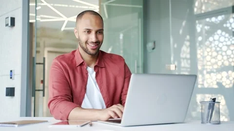 Smiling businessman working on a laptop while sitting at a workplace  Stock Footage 311623858