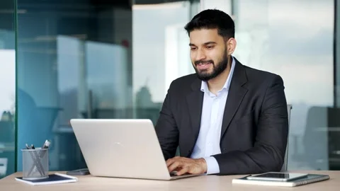 Smiling businessman working on a laptop while sitting at a workplace Stock Footage 318219604