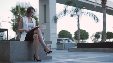 Smiling businesswoman checking notes in work diary during break outdoors Video stock 132038005