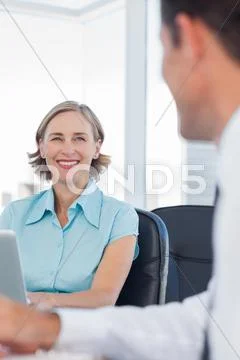 Smiling businesswoman talking to her colleague Stock Photos