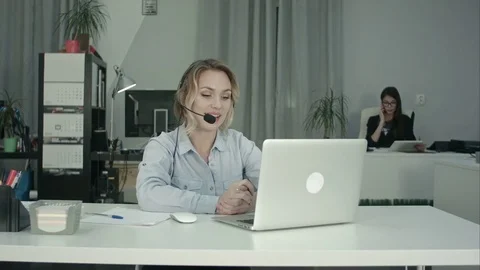Smiling call center operator working with laptop using headset in office Vídeos de archivo 71106211