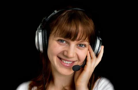 Smiling call centre operator with headset at workplace isolated on black Stock Photos