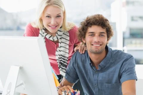 Smiling casual couple using computer in bright office Stock Photos