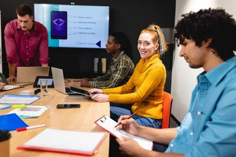 Smiling caucasian app developers with multiracial colleagues during meeting in Stock Photos