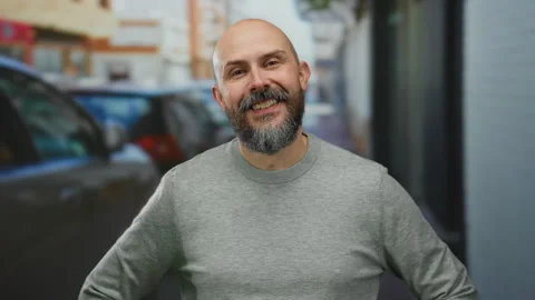 Smiling caucasian man with beard and bald head stands outdoors on an urban .. Stock Footage 311496324
