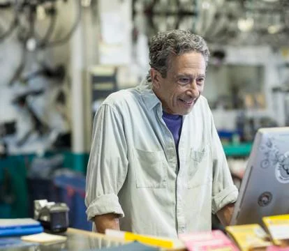 Smiling Caucasian man using computer in bicycle shop Stock-Fotos
