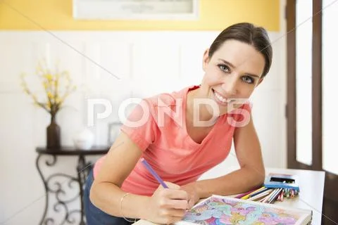 Smiling Caucasian Woman Drawing In Coloring Book