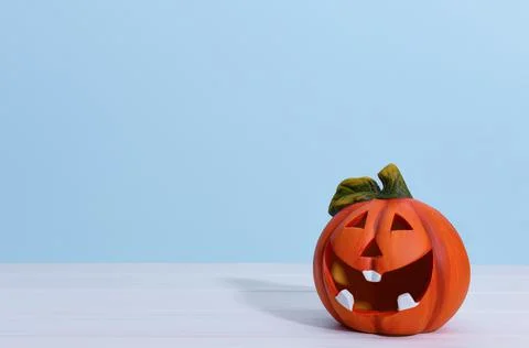 Smiling ceramic pumpkin lantern on a blue background. Stock Photos