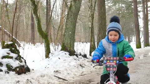 Smiling charming 4 years old boy on bicycle in winter time in park front view Stock Footage 149552418