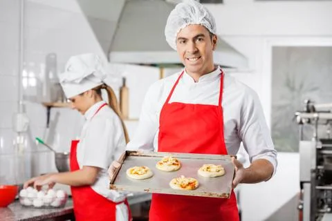 Smiling Chef Holding Small Pizzas On Baking Sheet At Kitchen Stock Photos