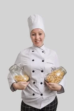Smiling chef holding two jars filled with different pasta shapes Stock Photos
