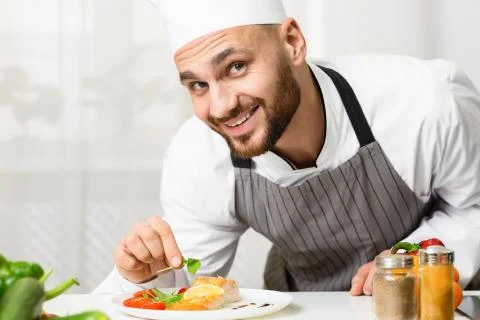 Smiling Chef Man Decorating Roasted Salmon Steak In Kitchen Stock-Fotos