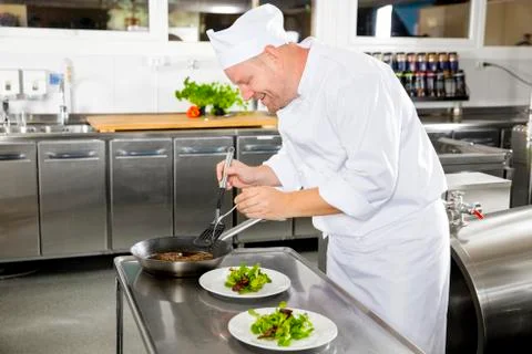 Smiling chef prepares steak dish at restaurant Stock Photos
