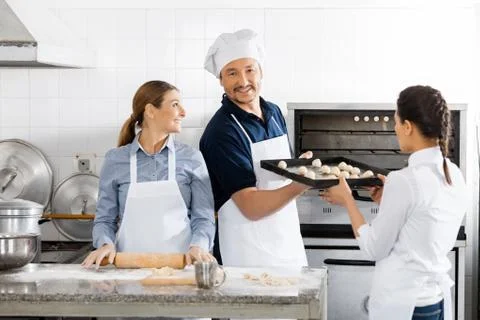 Smiling Chef Taking Baking Sheet From Colleague By Oven Stock Photos