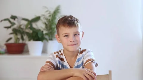 Smiling child boy  looks at the camera sitting at the table at home. Stock Footage 273280451