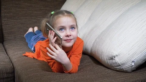 Smiling child on the couch with phone Stock Footage 124363746