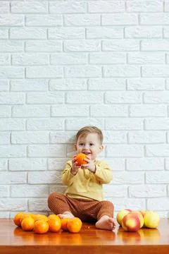 Smiling child eats one fresh juicy red apple. Healthy fruits for young childr Stock Photos