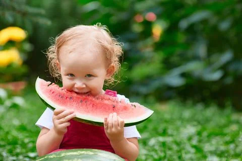 Smiling child eats watermelon outside in summer. Stock Photos