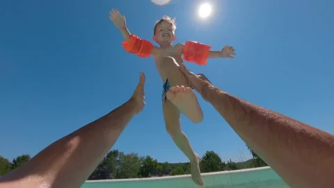 Smiling child leaping into pool with floaties 스톡 동영상 322779195