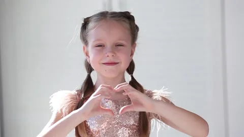 Smiling child looking at the camera, making a heart with his hands. Stock Footage 145828234
