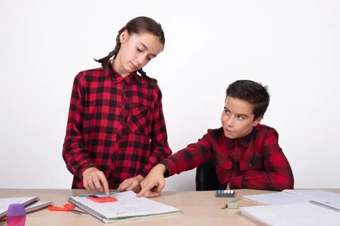 Smiling child pointing the result of a problem to a girl in the notebook Stock Photos