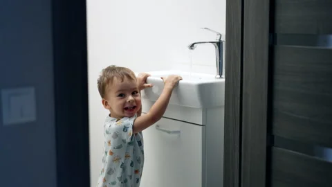 Smiling child standing at the sink open the tap. Stock Footage 254451394