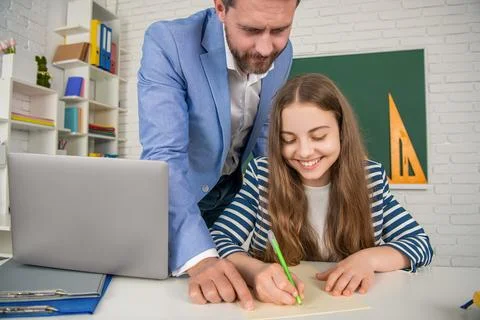 Smiling child with tutor in classroom use laptop Foto stock
