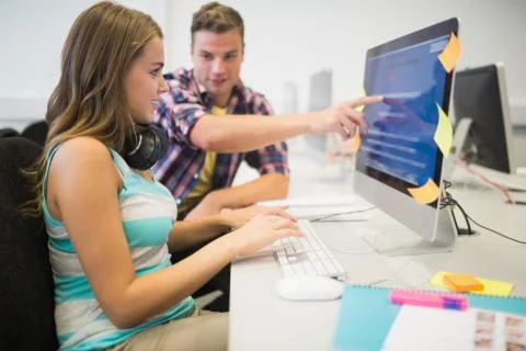 Smiling classmates doing an assignment together in the computer room Stock Photos