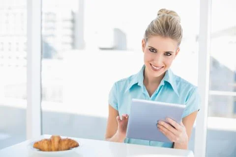 Smiling classy woman using tablet while having breakfast Stock Photos