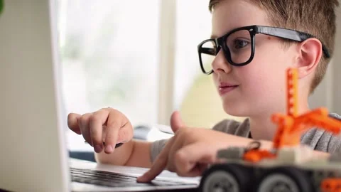 Smiling clever boy in eyeglasses learning programming. Robotics, STEM. 스톡 동영상 196792996