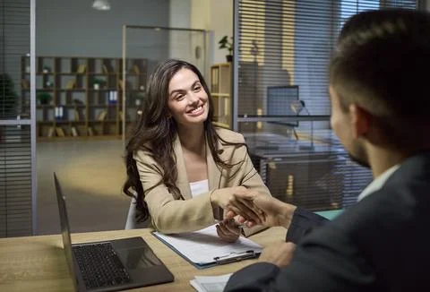 Smiling client shaking hands with advisor after contract signing in office Stock Photos