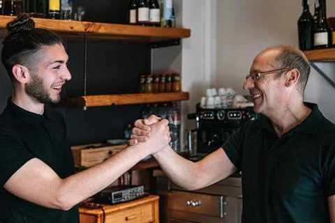 Smiling co-workers shaking hands. Work colleagues with a good relationship. Stock Photos