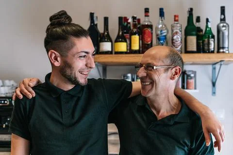Smiling co-workers in their small, newly opened company. Coworkers looking at Stock Photos
