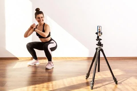 Smiling coach teaching correct squatting technique, recording tutorial video of 스톡 사진