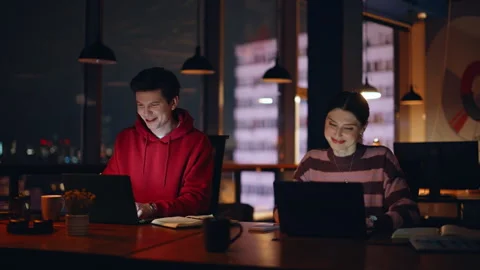 Smiling colleagues working overtime at computers sitting night workspace closeup Stock Footage 340111513