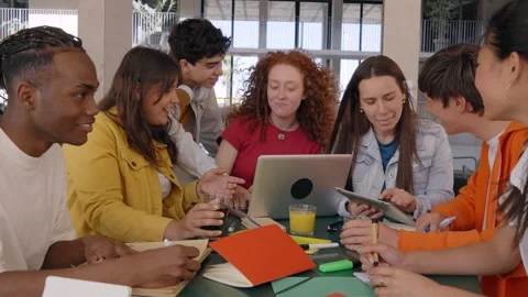Smiling college classmates using laptops in campus cafeteria. Group cheerful Stock Footage 241260395
