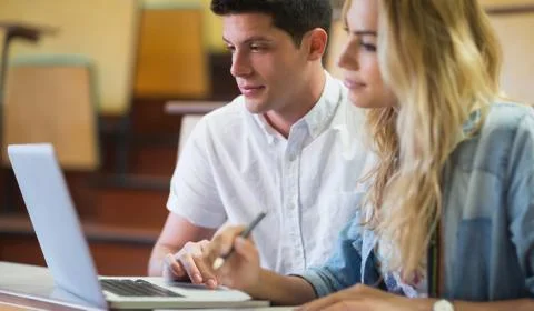 Smiling college students using laptop 스톡 사진