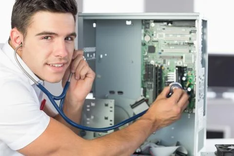 Smiling computer engineer examining hardware with stethoscope Stock Photos