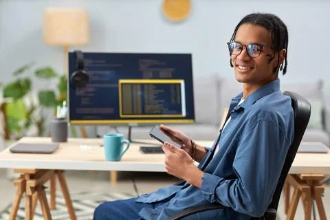 Smiling computer programmer holding tablet and writing code at workplace Stock Photos