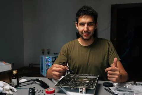 Smiling computer technician showing thumbs up gesture while fixing motherboard Stock Photos
