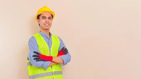 Smiling confident Asian construction worker wearing safety helmet and vest,.. Stock Photos