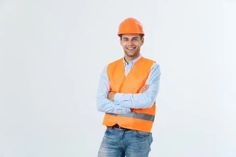 Smiling construction engineer posing with arms crossed. Isolated over grey 스톡 사진