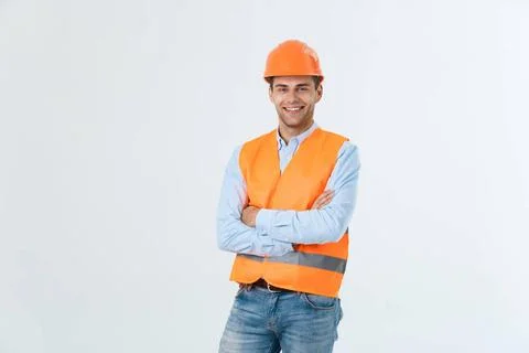 Smiling construction engineer posing with arms crossed. Isolated over grey... Stock Photos