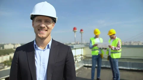 Smiling construction engineer in safety helmet looking camera, skilled architect 스톡 동영상 117218830