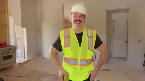 A Smiling Construction Worker Dressed in Safety Gear Working at a Busy Building Vidéo 308358106