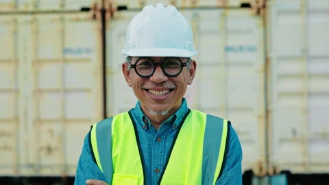 Smiling Construction Worker in Safety Vest Stands Confidently at a Shipping Yard Stock Footage 306185907