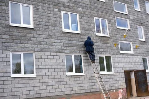 Smiling construction worker on step ladder under the house roof Stock Photos