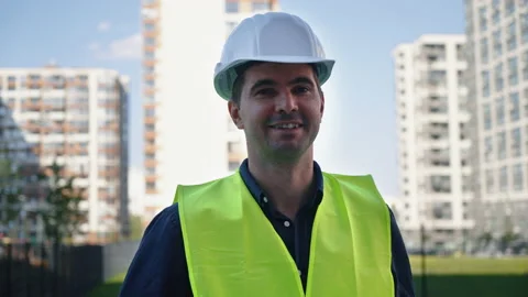 Smiling contractor in hard hat against multistory buildings Stock Footage 161807003