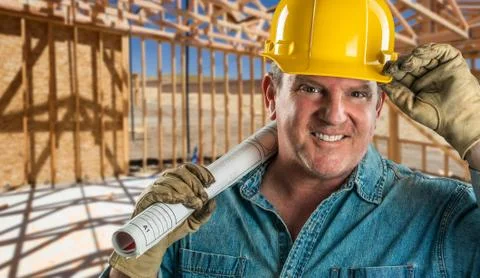 Smiling Contractor in Hard Hat Holding Floor Plans At Construction Site. Stock-Fotos