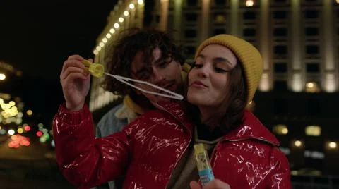 Smiling couple blowing soap bubbles outdoor. Pair enjoying date on urban street. Fotos Stock